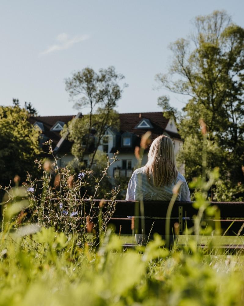 Frau sitzt auf einer Bank im Grünen
