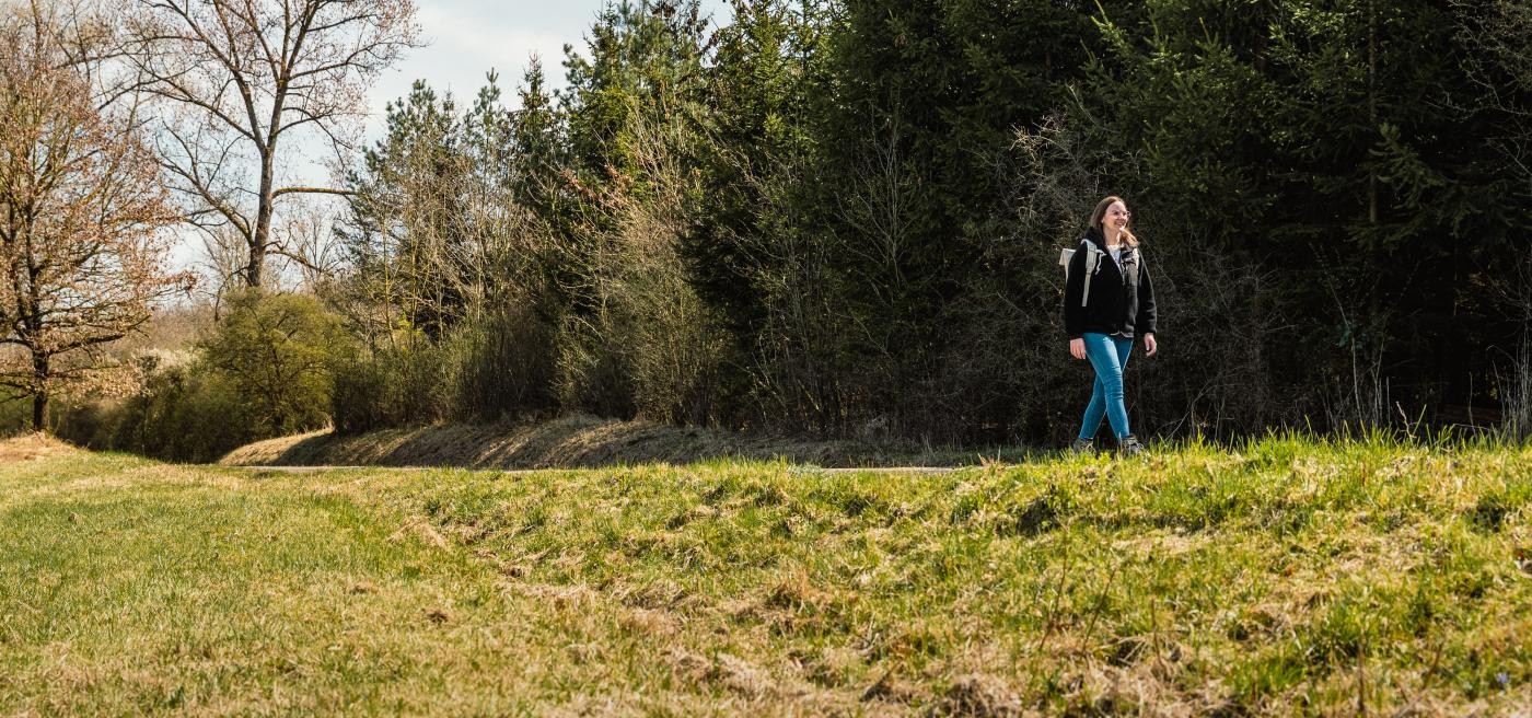 Frau wandert an einem Wald entlang