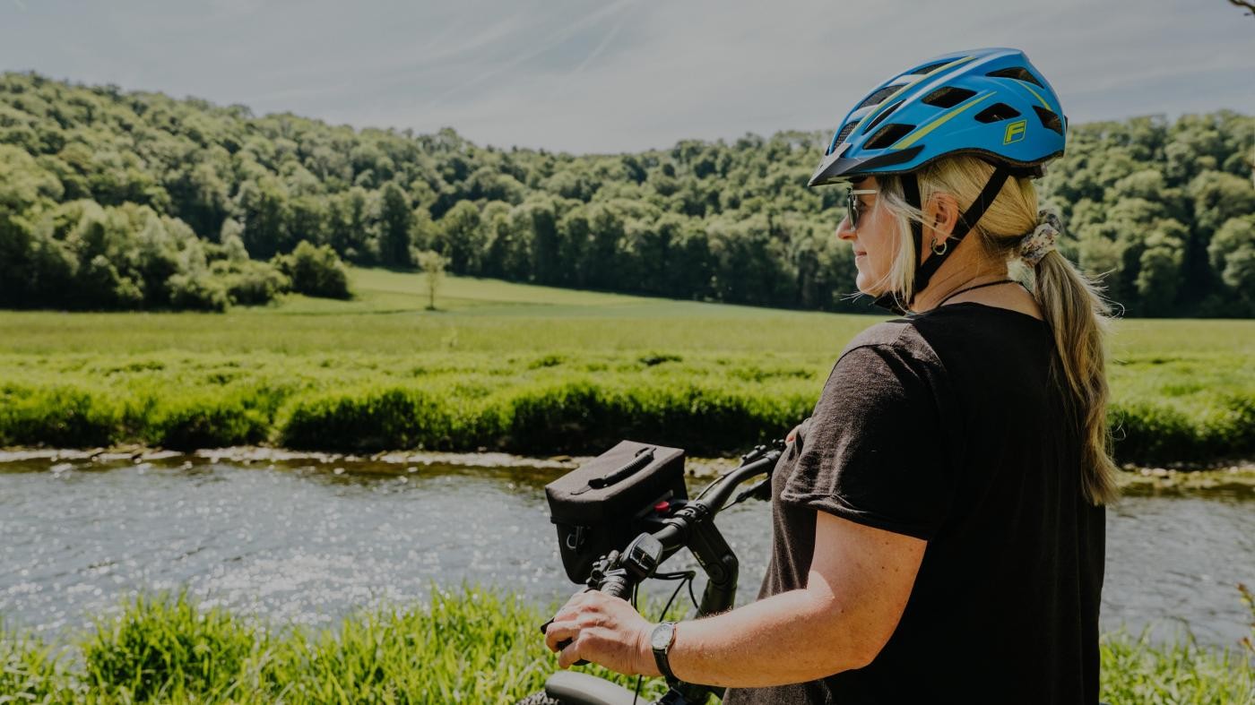 Eine Frau mit Fahrrad blickt auf die Jagst