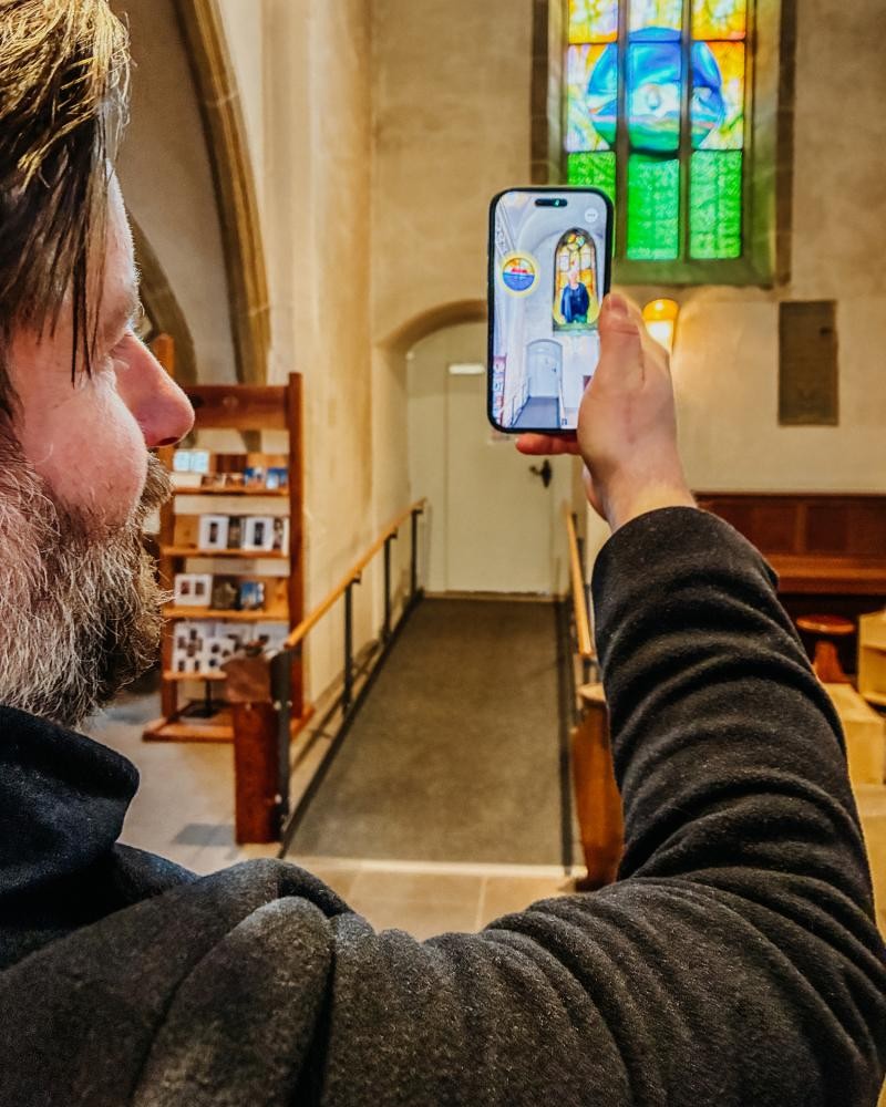 Stadtführerin steht lächeld vor dem Rathausturm und spricht mit einer Menschengruppe