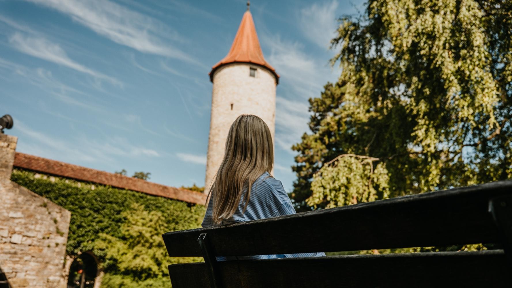 Frau sitzt auf einer Bank und blickt auf den Diebsturm