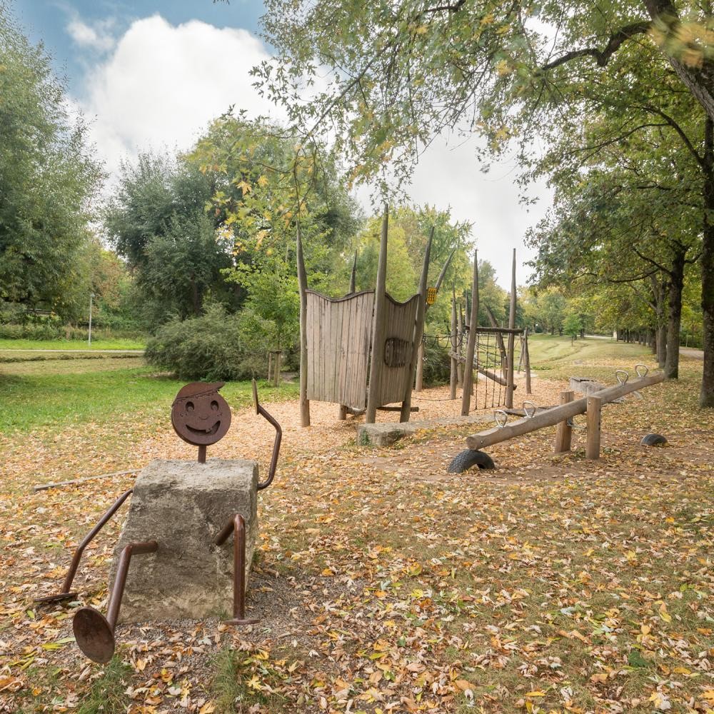 Zu sehen ist ein Spielplatz mit verschiedenen Spielgeräten, wie beispielsweise einer Wippe und einem Klettergerüst